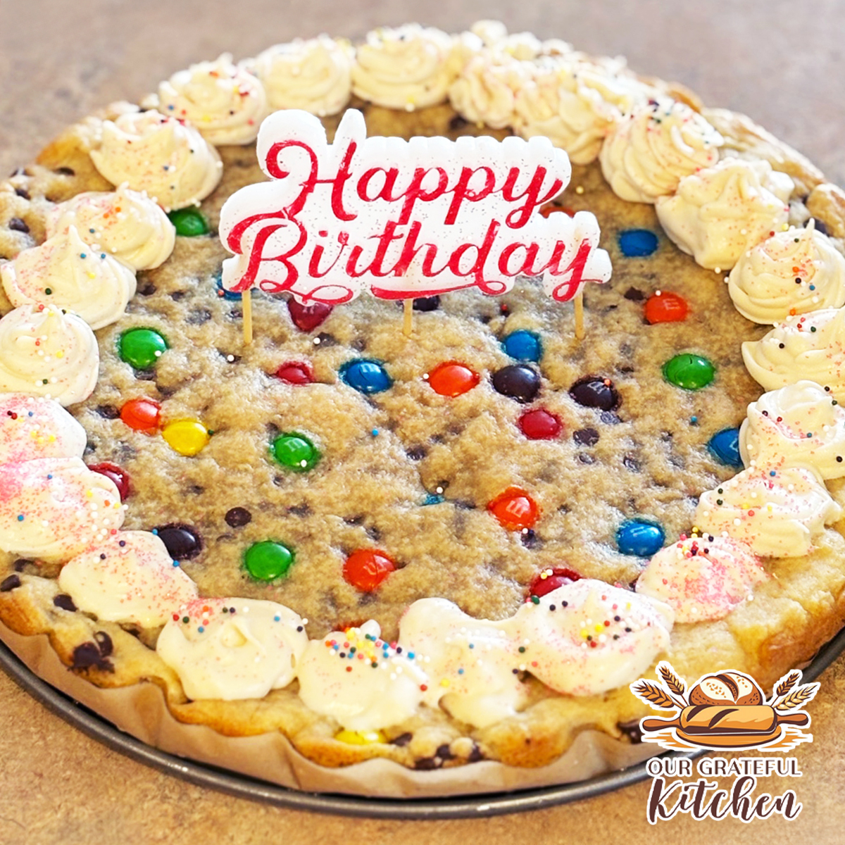 Chocolate chip cookie cake decorated with buttercream frosting and M&M candies for a birthday celebration