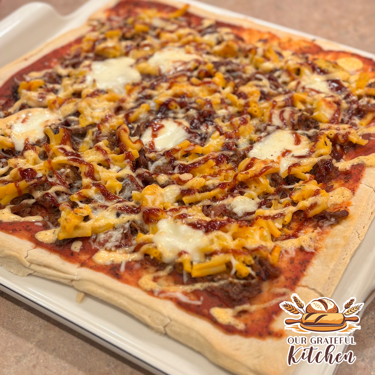 BBQ pulled pork pizza topped with melted mozzarella, macaroni and cheese, barbecue sauce drizzle, and ranch dressing on a homemade pizza crust