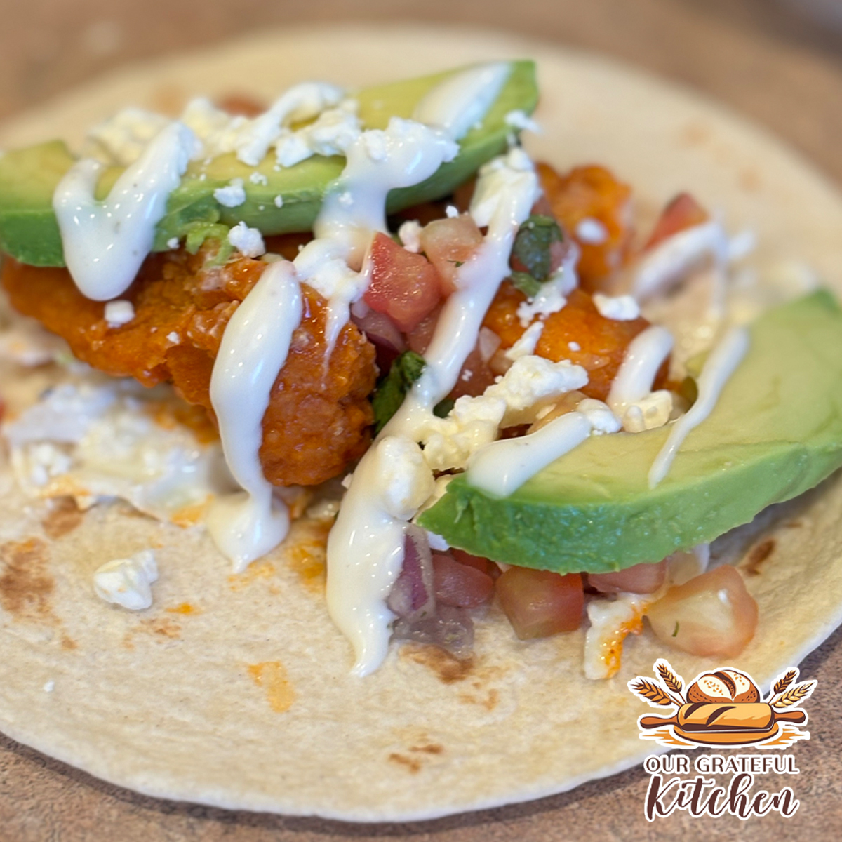 buffalo chicken bacon ranch taco with avocado pico feta and ranch drizzle close up