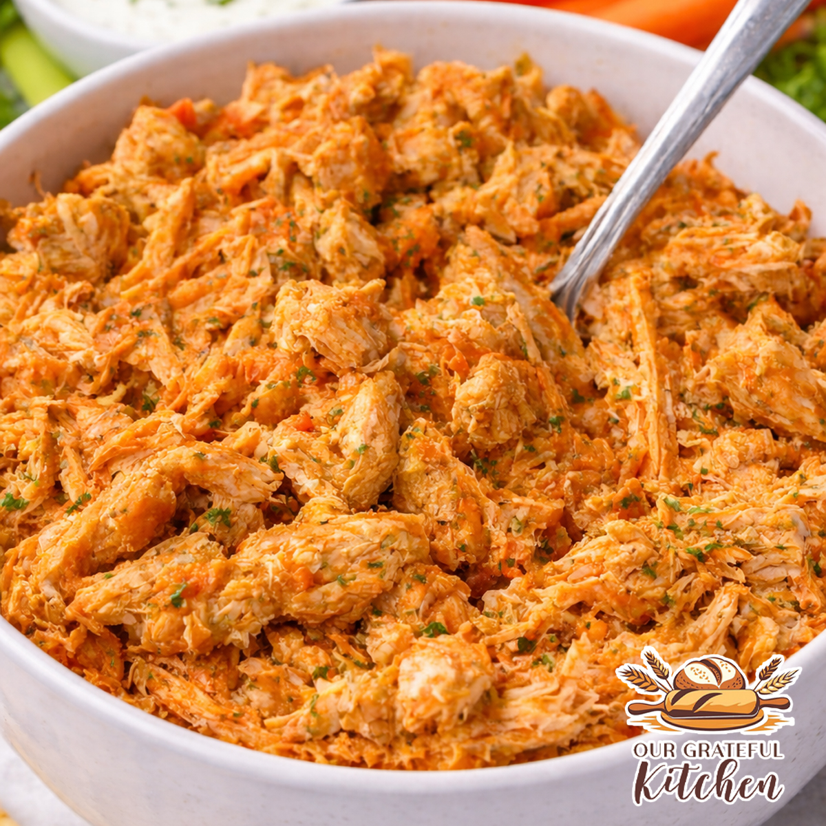 Shredded buffalo chicken made in the Instant Pot, served in a bowl with subtle fresh herbs mixed in, with carrots, celery, and ranch dressing on the side