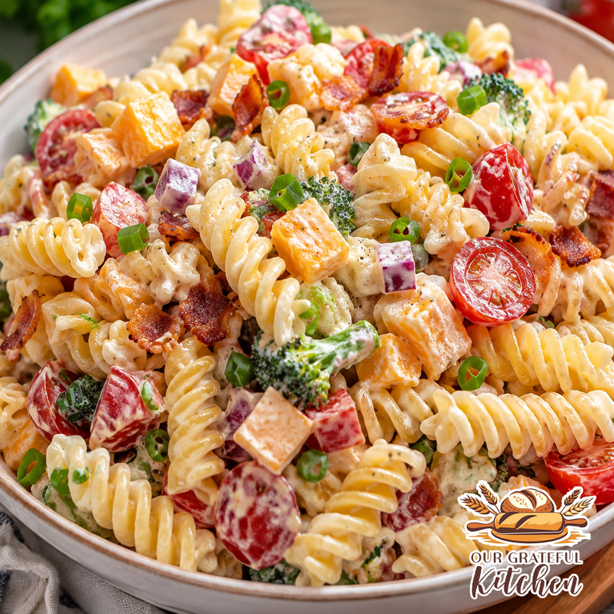 Creamy Bacon Ranch Pasta Salad made with rotini pasta, crispy bacon, sharp cheddar cheese, broccoli, cherry tomatoes, red onion, and homemade ranch dressing in a serving bowl.