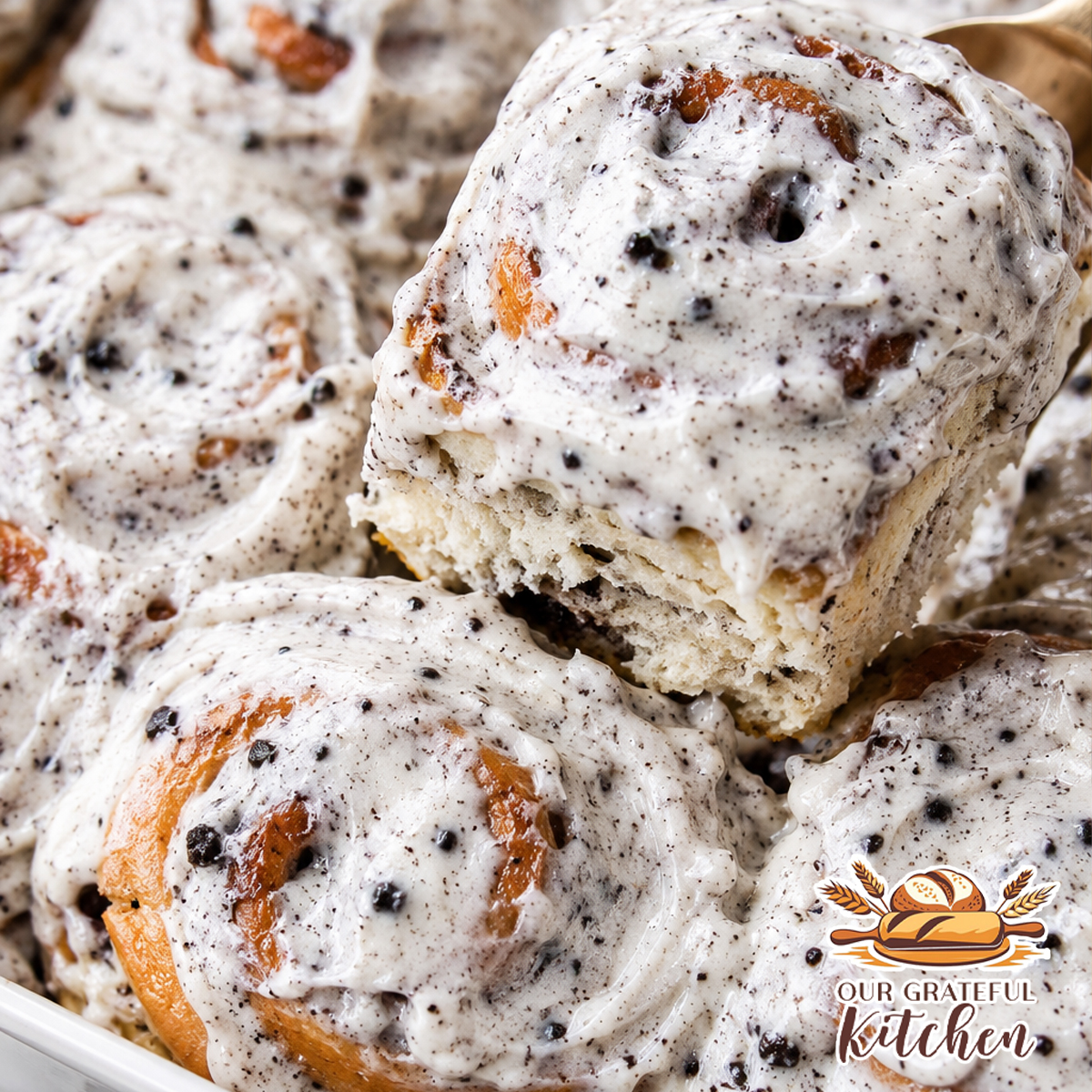 Soft homemade Oreo cinnamon rolls topped with Oreo cream cheese frosting in a white baking dish with crushed Oreo cookies sprinkled over the top.