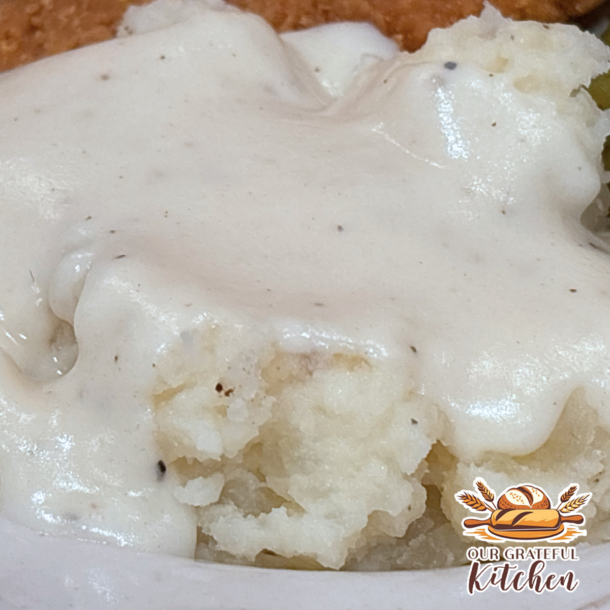 Homemade white country gravy served over mashed potatoes with chicken and green beans