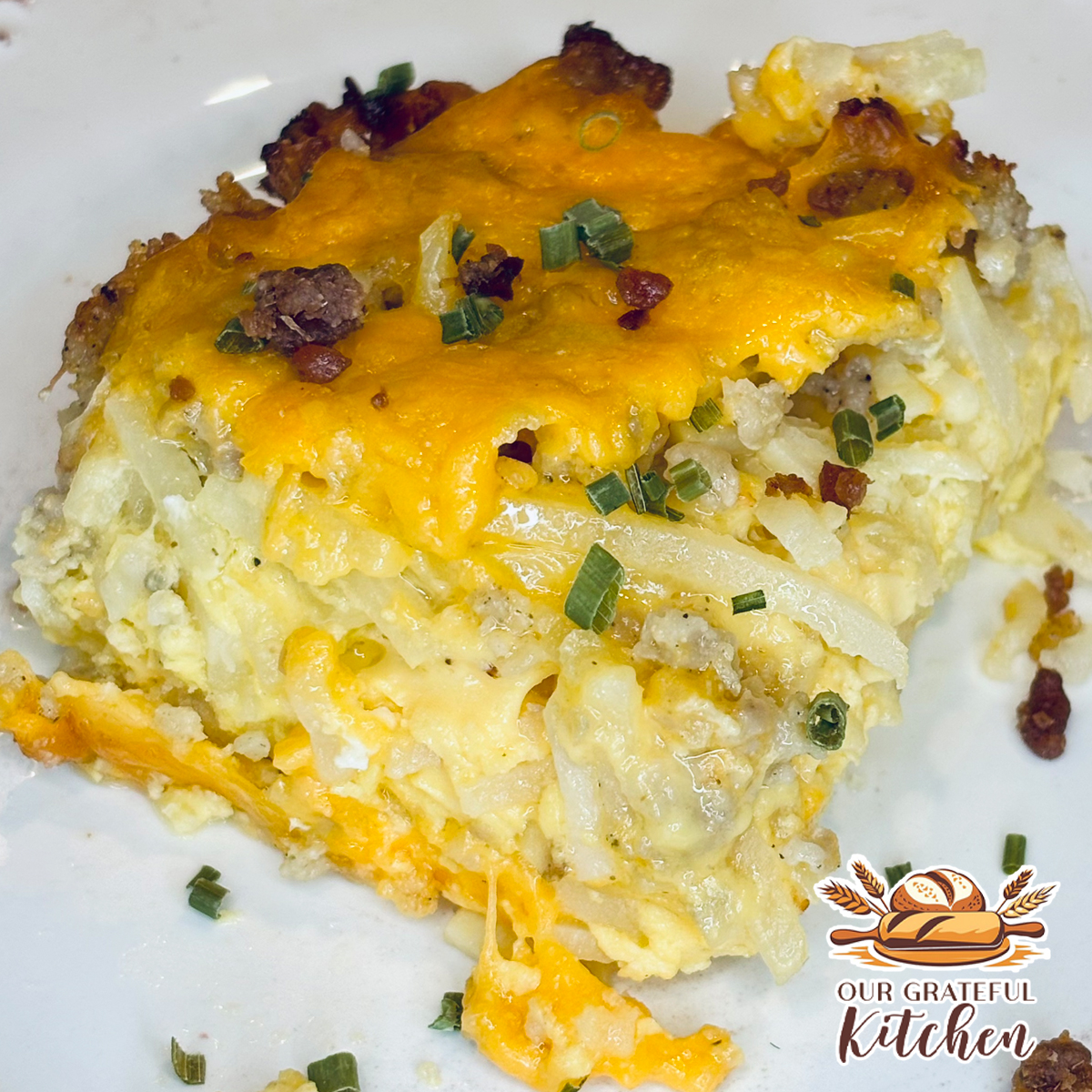 Slice of sausage hash brown breakfast casserole with eggs, breakfast sausage, potatoes, and cheddar cheese.